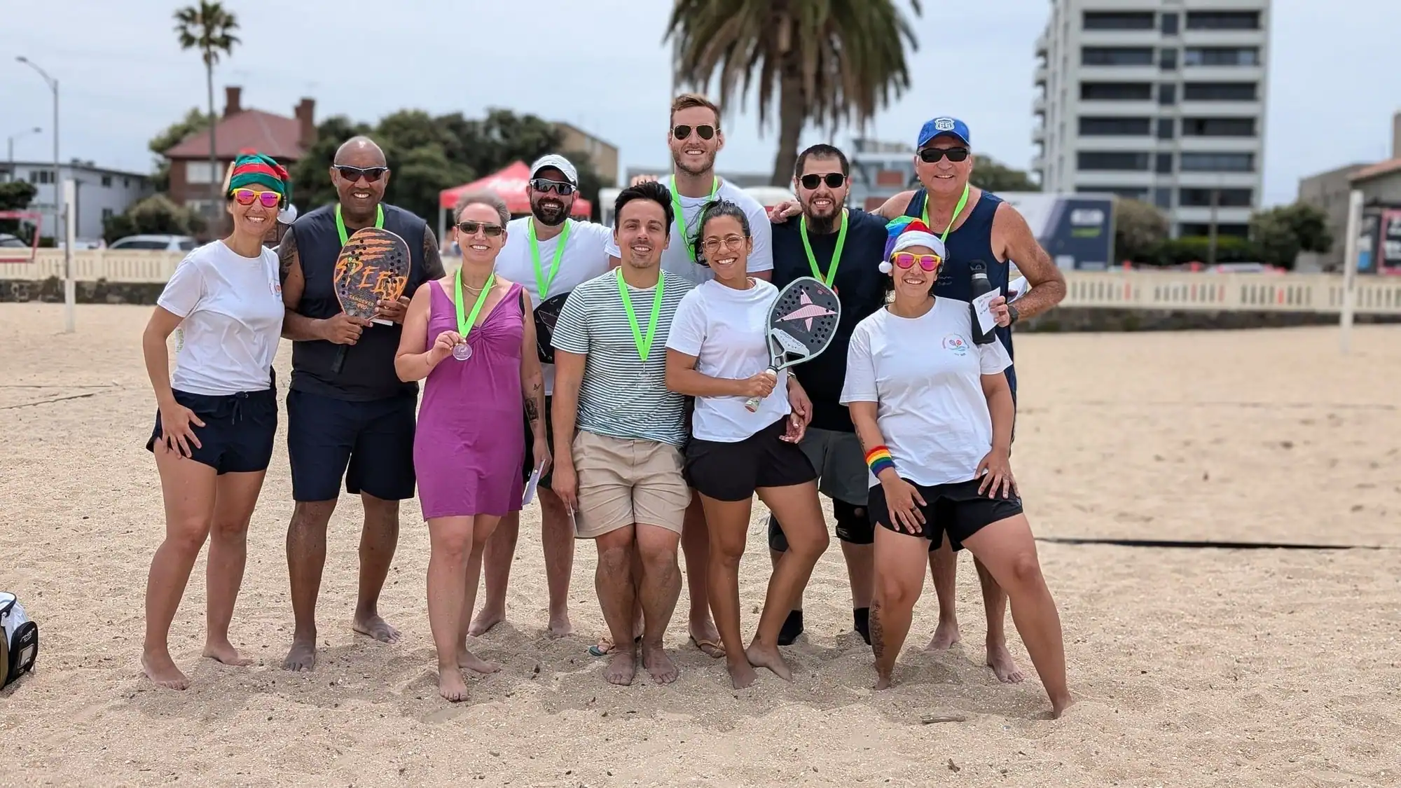 A group on the sand at West Beach after a session, medals round their necks and racquets in hand